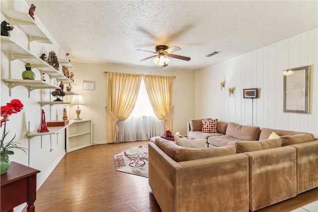 living area featuring visible vents, a textured ceiling, ceiling fan, and hardwood / wood-style flooring