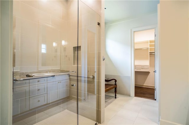 989 Beauregard Pkwy, Covington, LA 70433 - bathroom with a walk in closet, tile patterned flooring, vanity, tile walls, and a shower stall
