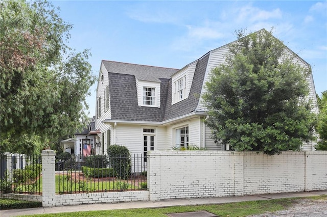 303 Audubon St, New Orleans, LA 70118 - dutch colonial with a gambrel roof, roof with shingles, and a fenced front yard