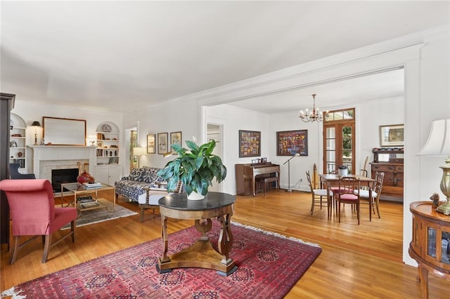 303 Audubon St, New Orleans, LA 70118 - living room with a chandelier, light wood-style flooring, crown molding, a fireplace, and built in shelves