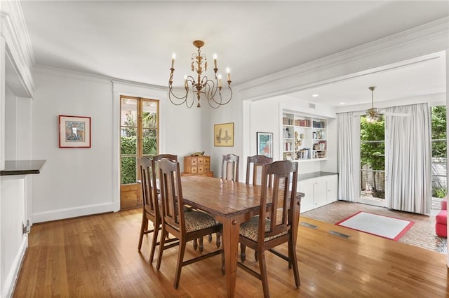 303 Audubon St, New Orleans, LA 70118 - dining room featuring a chandelier, wood finished floors, plenty of natural light, crown molding, and baseboards
