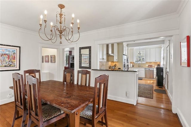 303 Audubon St, New Orleans, LA 70118 - dining room with a chandelier, light wood finished floors, and crown molding