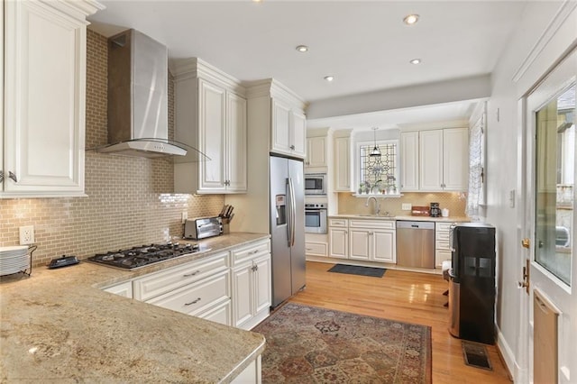 303 Audubon St, New Orleans, LA 70118 - kitchen featuring wall chimney exhaust hood, stainless steel appliances, a sink, light wood-type flooring, and backsplash