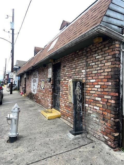 3801 Tchoupitoulas St, New Orleans, LA 70115 - view of side of property with a shingled roof and brick siding