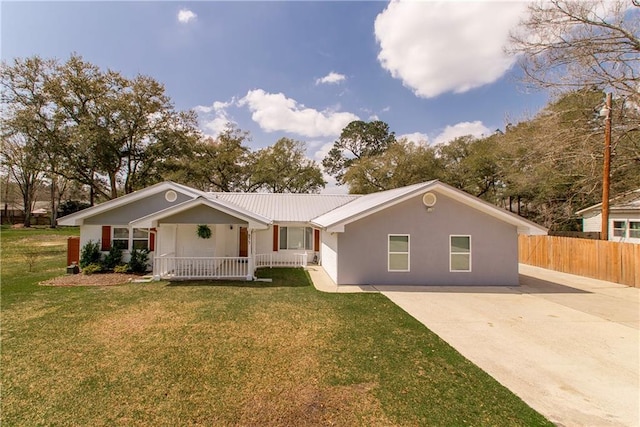 ranch-style home with metal roof, fence, a front lawn, stucco siding, and covered porch