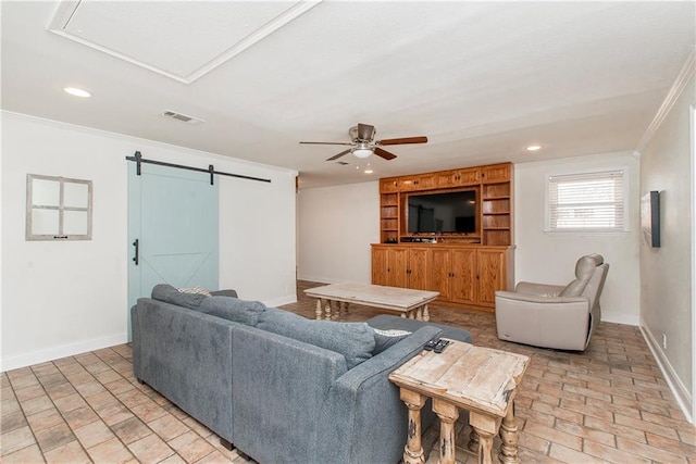 living room with baseboards, a barn door, ornamental molding, and visible vents