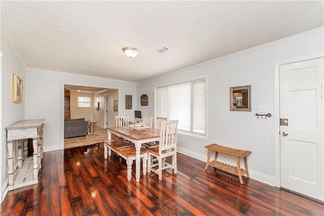 dining room featuring baseboards, a textured ceiling, ornamental molding, and wood finished floors