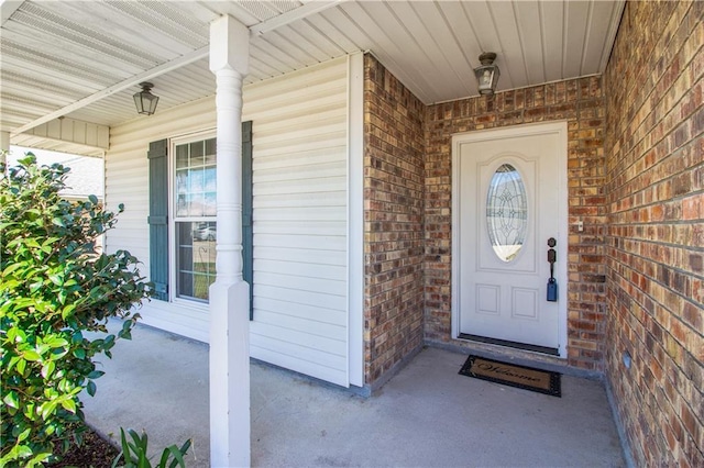 entrance to property featuring brick siding and a porch
