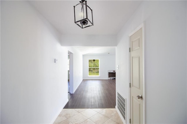 corridor featuring light tile patterned floors, baseboards, and visible vents