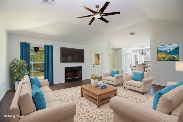 living area featuring visible vents, a fireplace, wood finished floors, ceiling fan with notable chandelier, and vaulted ceiling