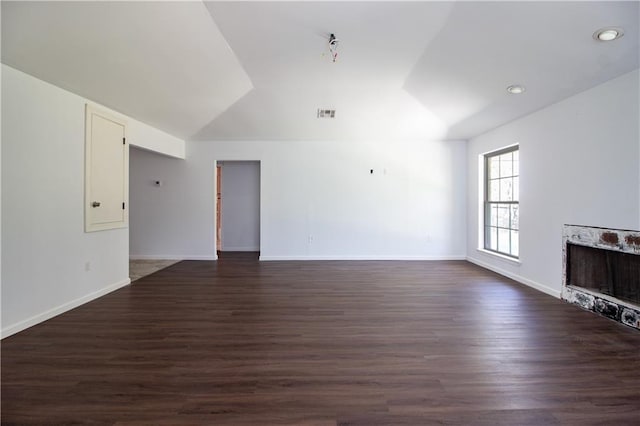 unfurnished living room featuring visible vents, dark wood-type flooring, lofted ceiling, and baseboards