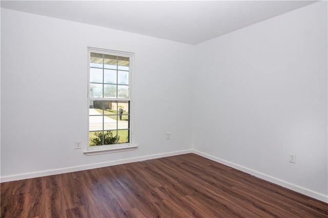 spare room with dark wood-style flooring and baseboards