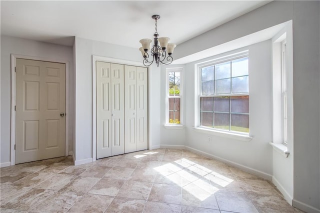 unfurnished bedroom with baseboards, a closet, and a chandelier