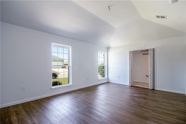 spare room with dark wood-style floors, visible vents, baseboards, and vaulted ceiling