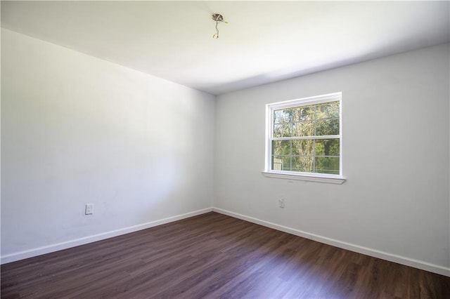 unfurnished room featuring baseboards and dark wood-style flooring