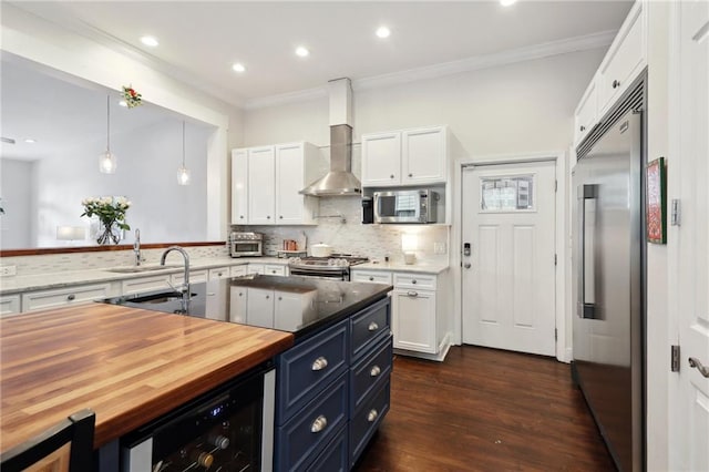 740 Florida Blvd, New Orleans, LA 70124 - kitchen featuring stainless steel appliances, butcher block countertops, white cabinetry, ornamental molding, and wall chimney exhaust hood