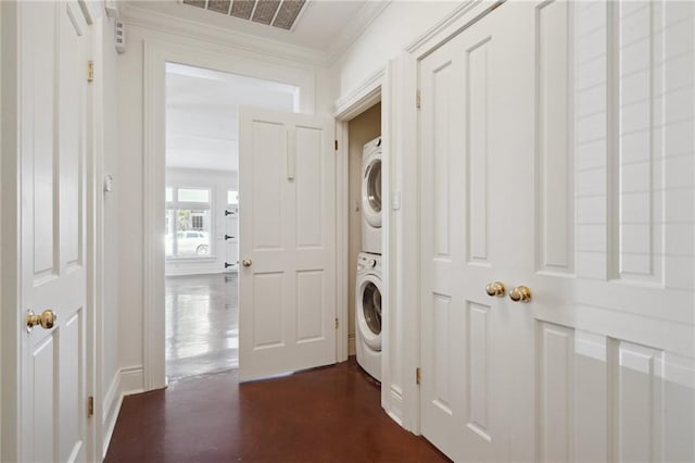 washroom with stacked washer / dryer and ornamental molding