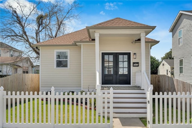 8820 Cohn St, New Orleans, LA 70118 - bungalow-style house featuring a shingled roof, a fenced front yard, and french doors