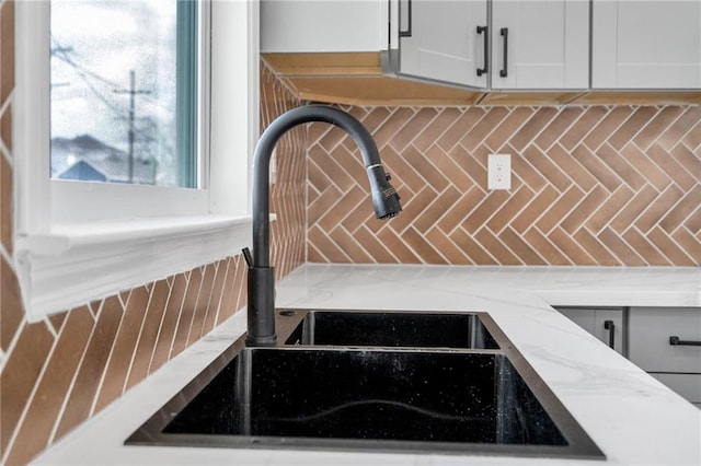 8820 Cohn St, New Orleans, LA 70118 - room details featuring white cabinetry, light stone countertops, a sink, and backsplash