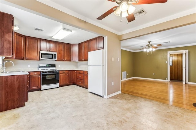 kitchen with stainless steel microwave, gas range, a sink, visible vents, and freestanding refrigerator