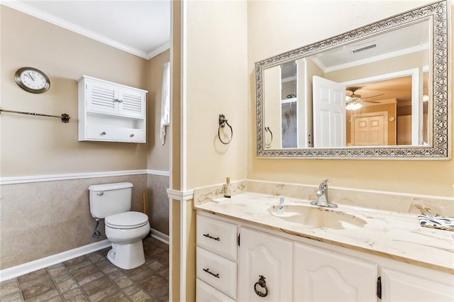 bathroom with toilet, wainscoting, visible vents, ceiling fan, and ornamental molding