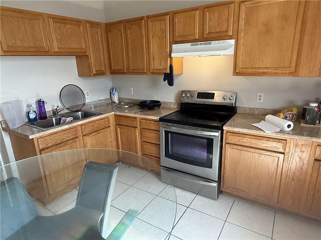 1827 S Rampart St, New Orleans, LA 70113 - kitchen with stainless steel electric range oven, under cabinet range hood, a sink, light tile patterned flooring, and brown cabinets