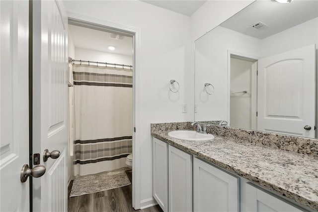 bathroom with vanity, a shower with curtain, visible vents, toilet, and wood finished floors