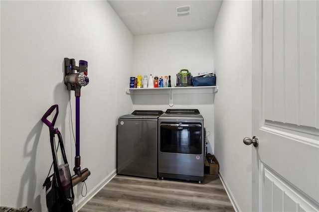 washroom featuring laundry area, wood finished floors, baseboards, and washing machine and dryer