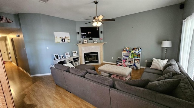 living area featuring wood finished floors, baseboards, a ceiling fan, and a tile fireplace
