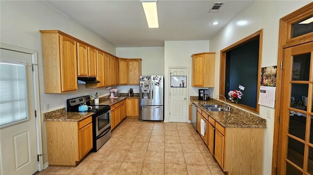 kitchen with under cabinet range hood, visible vents, dark stone counters, appliances with stainless steel finishes, and a sink