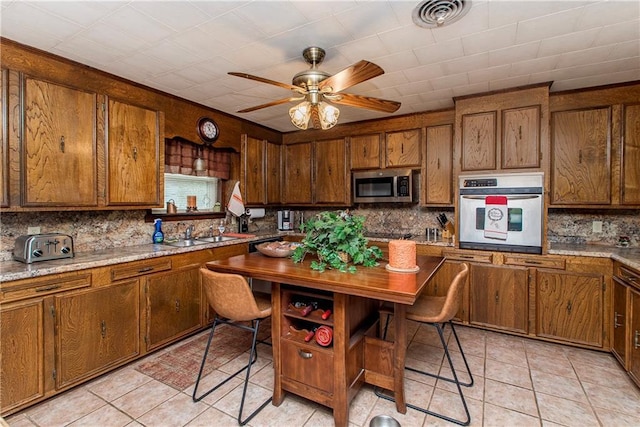 59345 Twin Pines Rd, Bogalusa, LA 70427 - kitchen featuring visible vents, brown cabinetry, ceiling fan, appliances with stainless steel finishes, and backsplash