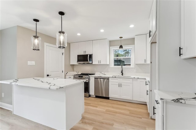 156 Belle Terre Blvd, Covington, LA 70433 - kitchen with stainless steel appliances, a sink, light wood finished floors, white cabinetry, and light stone counters