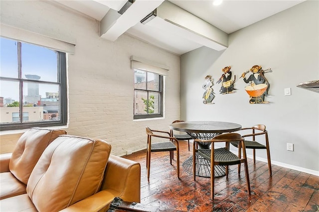 dining area featuring baseboards, brick wall, hardwood / wood-style flooring, and beamed ceiling