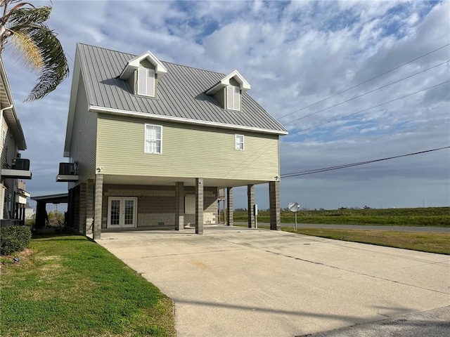 100 Deer Range Ln, Port Sulphur, LA 70083 - back of house featuring french doors, metal roof, a lawn, driveway, and a carport