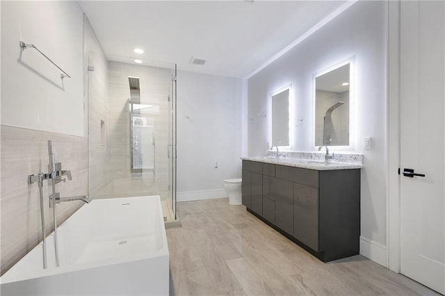 bathroom featuring a washtub, a stall shower, vanity, baseboards, and toilet