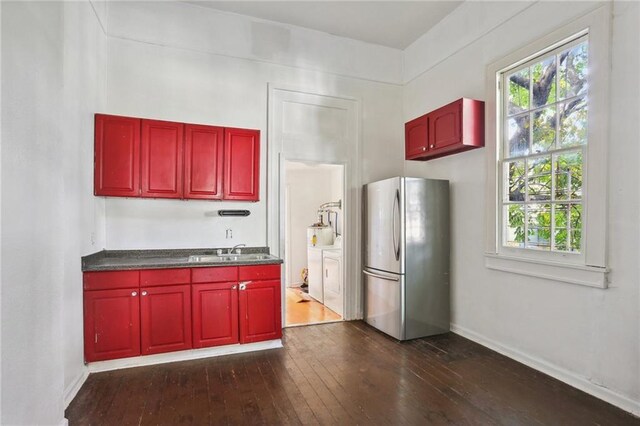 133234 Port St, New Orleans, LA 70117 - kitchen featuring dark wood-style flooring, washing machine and clothes dryer, a sink, freestanding refrigerator, and dark brown cabinets