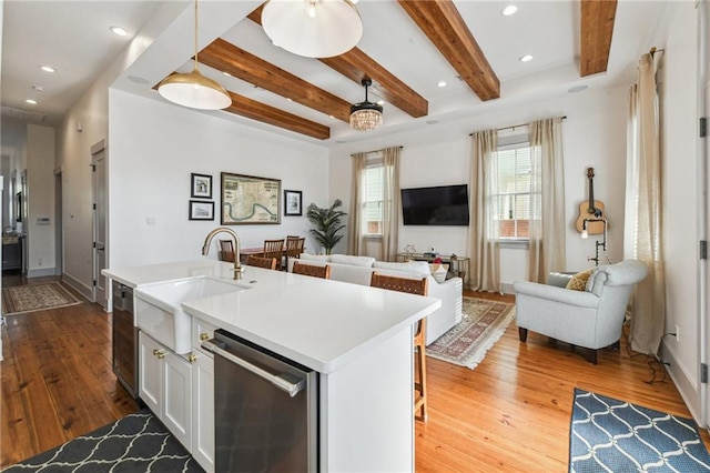 125 Elmira Ave, New Orleans, LA 70114 - kitchen featuring stainless steel dishwasher, hardwood / wood-style flooring, open floor plan, beamed ceiling, and white cabinets