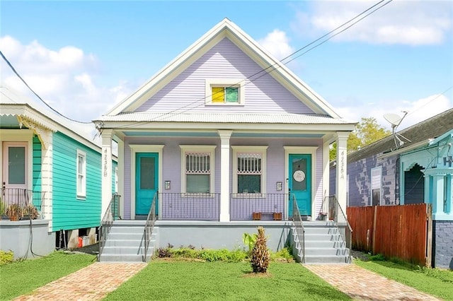 view of front facade with fence, a front yard, and a porch