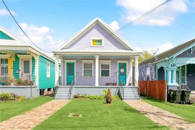 shotgun-style home featuring a porch and a front lawn