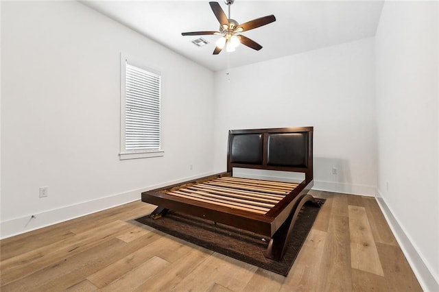 bedroom featuring baseboards, ceiling fan, visible vents, and wood finished floors