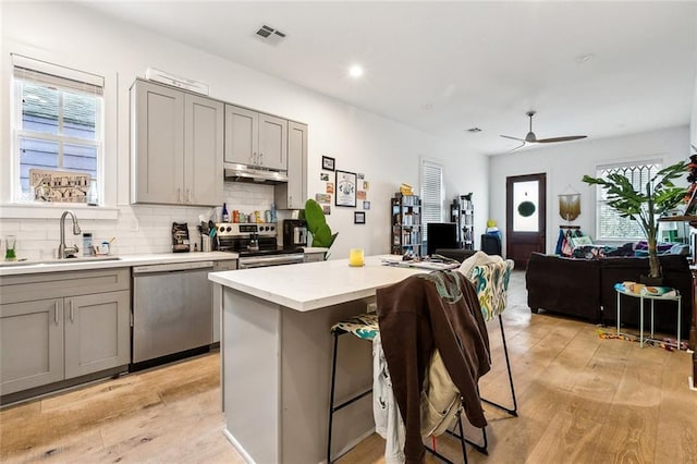 4235 Tulane Ave, New Orleans, LA 70119 - kitchen with appliances with stainless steel finishes, gray cabinetry, a sink, light wood finished floors, and recessed lighting