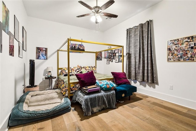bedroom featuring baseboards, visible vents, wood finished floors, and ceiling fan