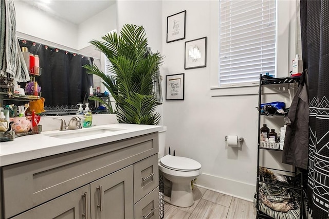 bathroom featuring baseboards, toilet, and vanity