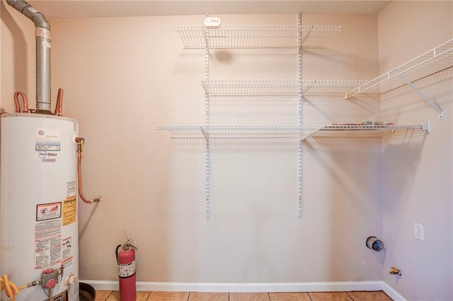 3800 Decomine Dr, Chalmette, LA 70043 - laundry room with tile patterned floors, gas water heater, baseboards, and laundry area