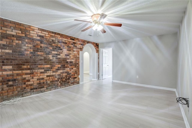 3800 Decomine Dr, Chalmette, LA 70043 - unfurnished room with baseboards, arched walkways, brick wall, visible vents, and a ceiling fan