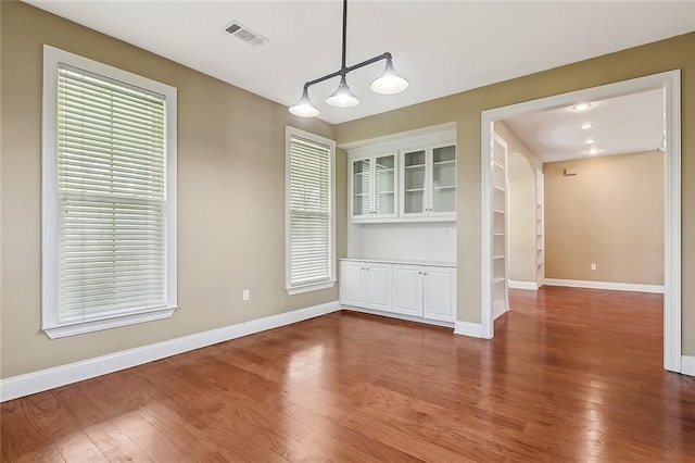 80055 Rollo Rd, Bush, LA 70431 - unfurnished dining area featuring baseboards, visible vents, a healthy amount of sunlight, and wood finished floors