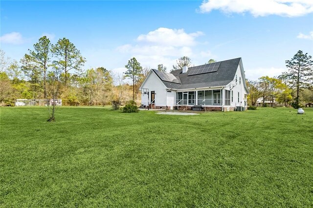 80055 Rollo Rd, Bush, LA 70431 - rear view of house with roof with shingles, roof mounted solar panels, entry steps, a sunroom, and a lawn