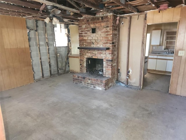 602 6th St, Pearl River, LA 70452 - unfurnished living room featuring wooden walls, a sink, and a brick fireplace