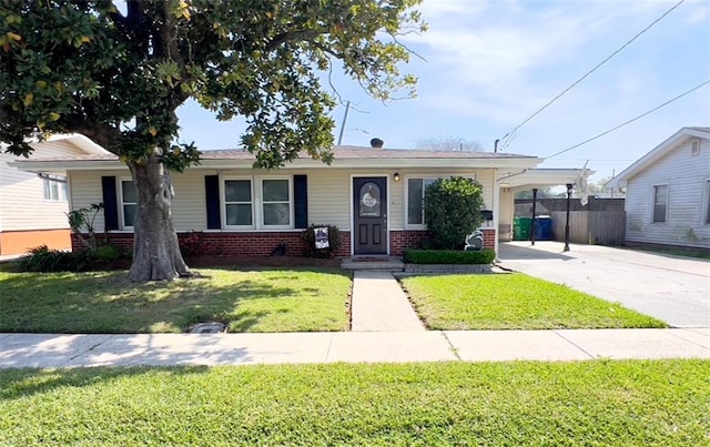 view of front of house with concrete driveway, fence, a front lawn, brick siding, and a carport