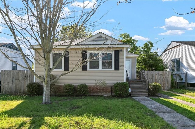 bungalow-style home with a front yard and fence